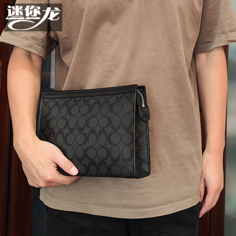 حقيبة يد رجالية من ماركة ميني دراجون (Mini dragon)، وتتميز بهيكلها الجلدي الصلب (Hard Leather Feel) ونقشة المربعات الكلاسيكية (Plaid) الأنيقة، مع شعار حرف الـ "O"