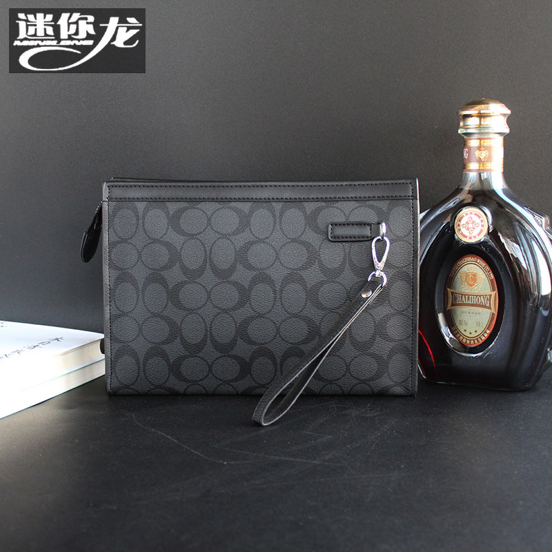 حقيبة يد رجالية من ماركة ميني دراجون (Mini dragon)، وتتميز بهيكلها الجلدي الصلب (Hard Leather Feel) ونقشة المربعات الكلاسيكية (Plaid) الأنيقة، مع شعار حرف الـ "O"